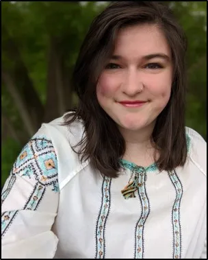 A portrait of Katelyn Evans. She is wearing an embroidered white shirt. 
